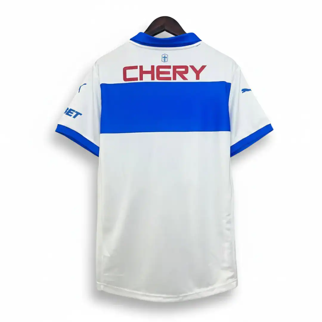 Camiseta de fútbol blanca con una franja horizontal azul en el medio, cuello azul y el logo rojo "CHERY" en la espalda, colgada en un gancho de madera sobre un fondo blanco.
