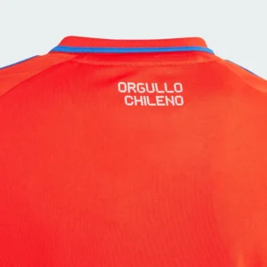 camiseta-futbol-roja-orgullo-chileno Vista trasera detallada de una camiseta de fútbol deportiva roja con cuello azul y rojo, mostrando el texto blanco 'ORGULLO CHILENO' impreso en la parte superior de la espalda, sobre una tela texturizada.