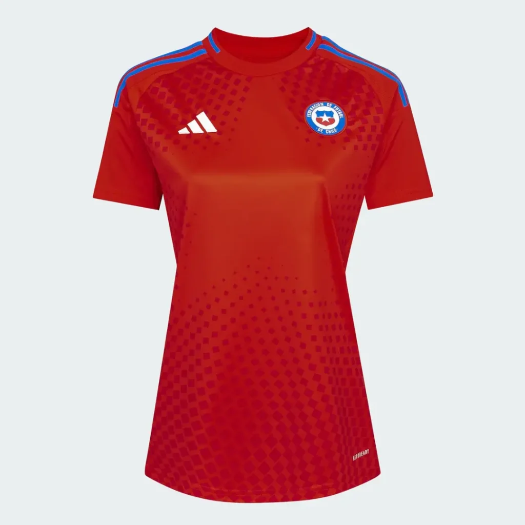 Camiseta de fútbol Adidas AEROREADY roja para mujer de la selección de Chile, con el escudo de la Federación de Fútbol de Chile en el pecho izquierdo, el logo de Adidas en el derecho, tres franjas azules en los hombros y un patrón gráfico de cuadrados que se desvanece hacia la parte inferior.