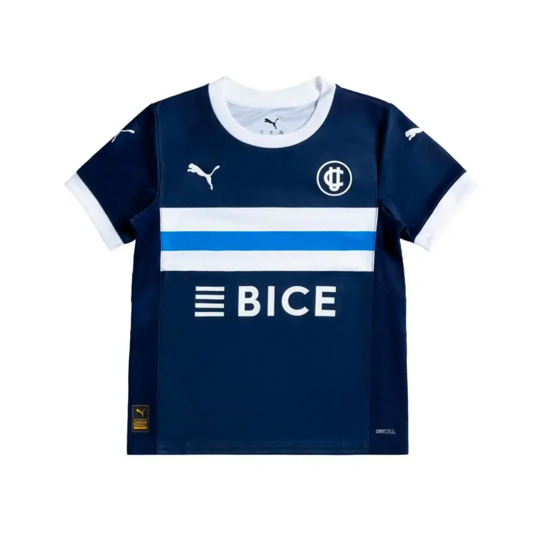 Camiseta de fútbol Puma de Club Deportivo Universidad Católica en azul marino, con cuello y puños blancos. Presenta dos franjas horizontales, una blanca y otra azul claro, en el pecho, junto al logo de Puma, el escudo de la UC y el patrocinador BICE en blanco.
