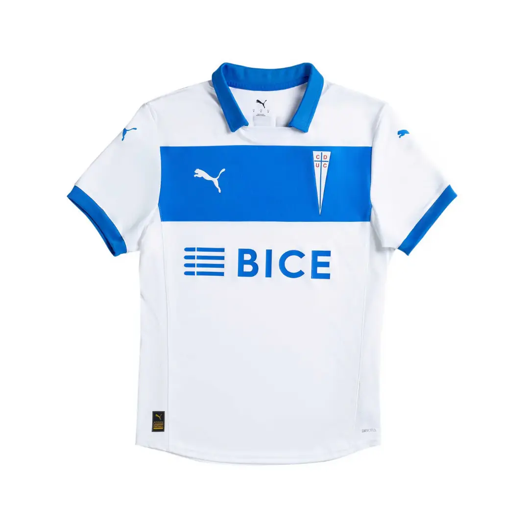 Camiseta de fútbol Puma de local de Universidad Católica, blanca con cuello azul y una franja horizontal azul en el pecho que muestra el logo blanco de Puma y el escudo del club. El patrocinador BICE está impreso en azul debajo de la franja. La camiseta tiene mangas cortas con ribetes azules y tecnología DRYCELL.