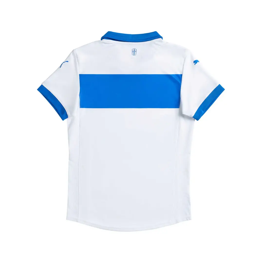 Vista trasera de una camiseta tipo polo blanca de manga corta, con una audaz franja horizontal azul brillante en la parte central. El cuello y los bordes de las mangas también son azules, y se aprecian pequeños logos azules de Puma en las mangas y un escudo del club debajo del cuello.