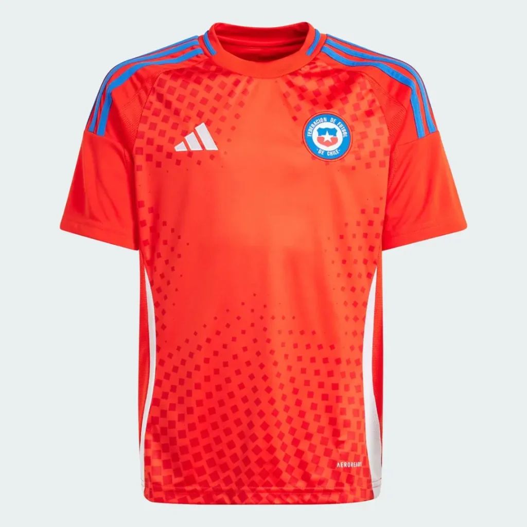 Camiseta de portero de fútbol para niños de la selección de Chile, color naranja brillante con un sutil patrón de cuadrados, cuello redondo, mangas cortas con franjas azules de Adidas en los hombros, el logo de Adidas blanco en el pecho derecho y el escudo de la Federación de Fútbol de Chile en el izquierdo.