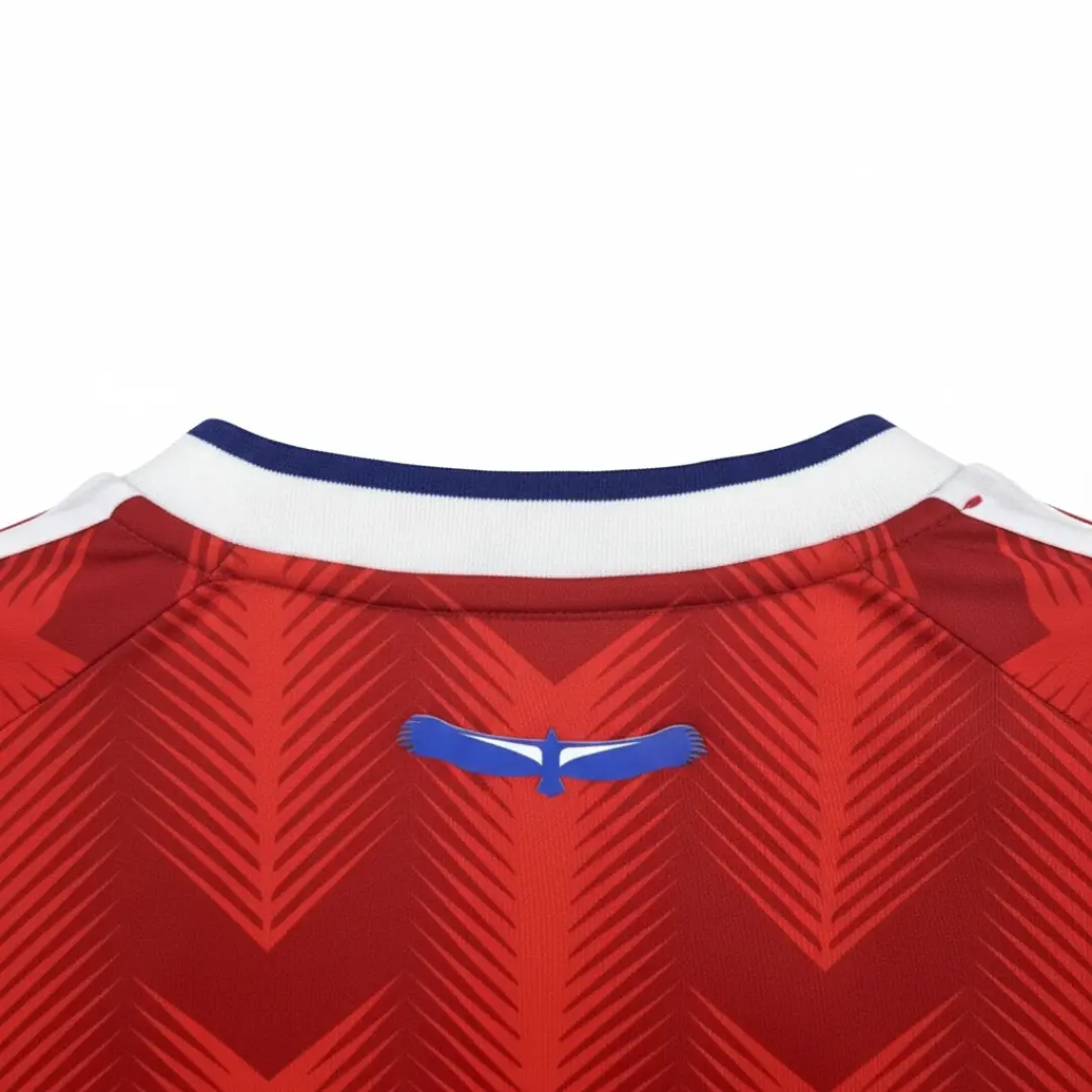 Vista trasera de una camiseta deportiva roja con un sutil patrón de chevrones, un cuello blanco con una delgada franja azul, y un emblema de pájaro azul estilizado en la parte superior de la espalda, colgada en una percha de madera, con una insignia verde en la esquina superior derecha que indica más de 4.000 reseñas y clientes felices. seleccion chilena 2025