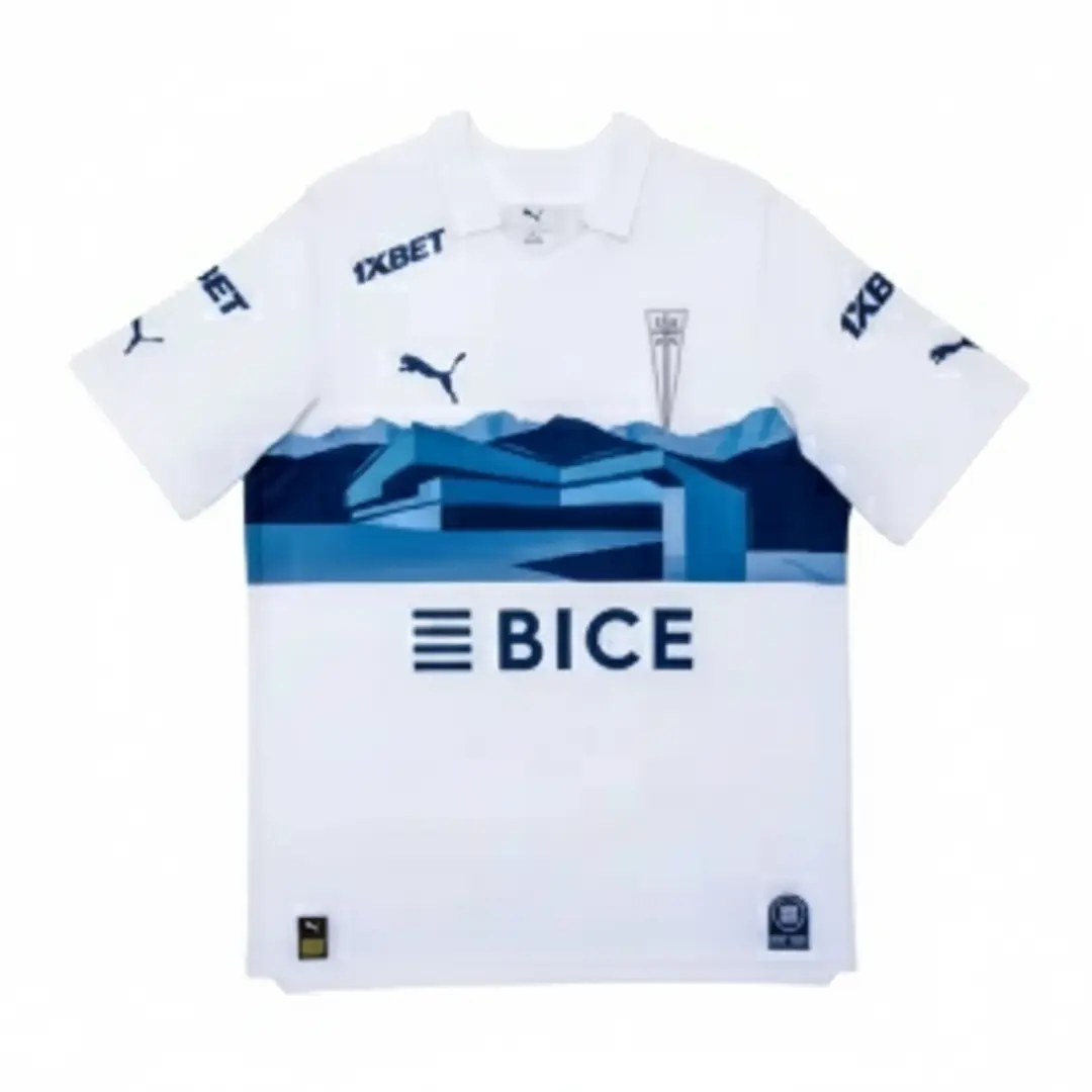 Camiseta de fútbol de local del Club Deportivo Universidad Católica, de color blanco con un diseño de montañas azules en el pecho y los logos de los patrocinadores 1XBET, BICE y Puma.
